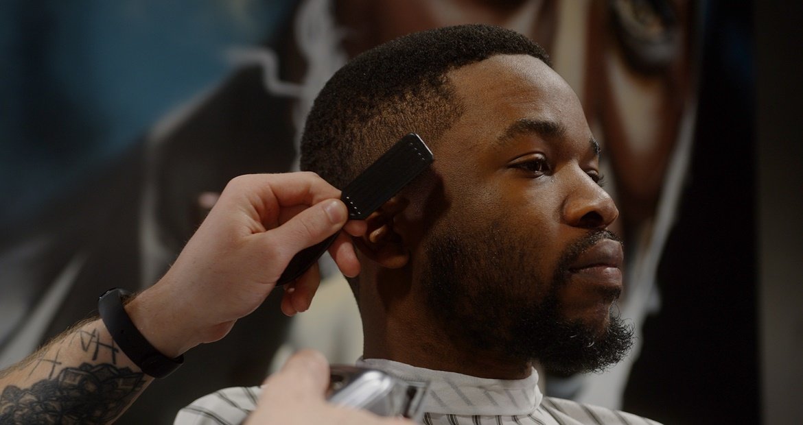 Barbeiro profissional realizando um corte para waves ou waves 360 no cabelo de um homem.